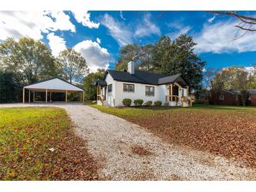 White brick house with black accents, new landscaping, and a detached carport at 412 E Jefferson St, York, SC 29745