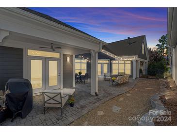 Relaxing back patio with brick pavers, string lights, and seating area at 16115 Lakeside Loop Ln, Cornelius, NC 28031