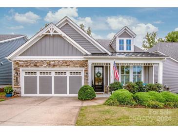 Gray house with stone accents, three-car garage, and manicured lawn at 8221 Festival Way, Charlotte, NC 28215