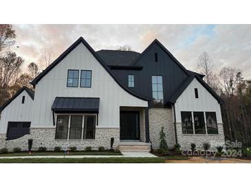 Stunning two-story home with modern farmhouse design, stone accents, and a black and white exterior at 136 Castleview Ln, Mooresville, NC 28115