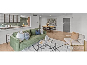 Modern living room featuring green velvet sofa and dining area at 1300 Queens Rd # 408, Charlotte, NC 28207