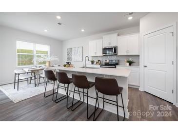 Modern kitchen with white cabinets, island with seating, and stainless steel appliances at 213 Brinkley Dr # 97, Kings Mountain, NC 28086