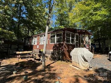 A charming brown cabin with a spacious porch and picnic table at 201 Deer Park Rd, Mount Gilead, NC 27306