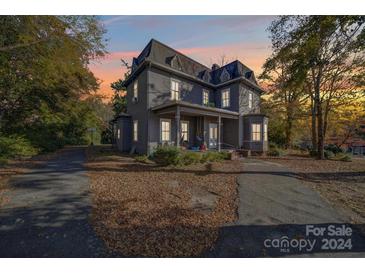 Two-story house with a wrap-around porch, mature trees, and a landscaped yard at 103 Brent St, Wadesboro, NC 28170