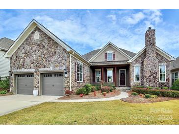 House exterior featuring stone facade, two-car garage, and landscaping at 14920 High Bluff Ct # 101, Charlotte, NC 28278