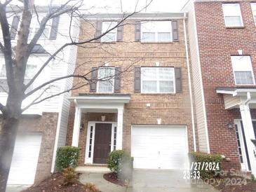 Brick front townhouse with a two-car garage and welcoming entryway at 14121 Winford Ln, Charlotte, NC 28262