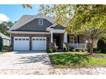 Two-story house with stone and shingle exterior, two-car garage, and covered porch at 11840 Meetinghouse Dr, Cornelius, NC 28031