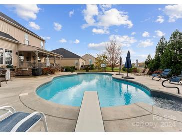 Inviting kidney-shaped pool with diving board, surrounded by lounge chairs and umbrellas at 120 Pecan Hills Dr, Mooresville, NC 28115