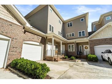 Three-story townhome with brick and siding exterior, attached garages, and front porch at 18819 Cloverstone Cir, Cornelius, NC 28031