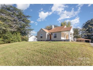 Tan house with brown roof, front porch, and well-manicured lawn at 2001 S Main St, Kannapolis, NC 28081