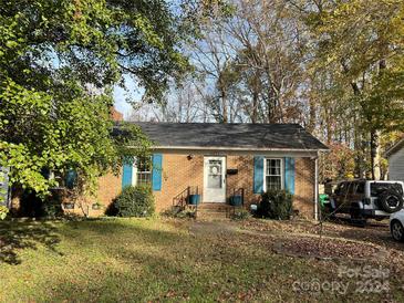 Brick ranch home with blue shutters, landscaping, and a spacious yard at 4821 Delivau Dr, Charlotte, NC 28215