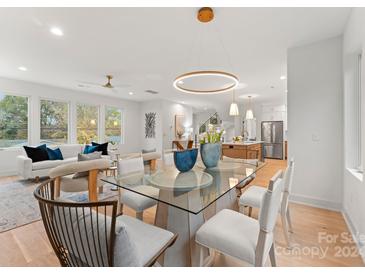 Open concept dining area with glass table and chairs, view into living room and kitchen at 2911 Hilliard Dr, Charlotte, NC 28205