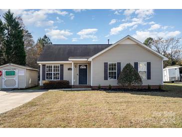 Tan house with a gray door, small yard, and shed at 618 White Oak Ln, Matthews, NC 28104