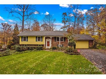 Brick and yellow-sided ranch home with a well-manicured lawn and driveway at 105 Buckingham Pl, Statesville, NC 28625