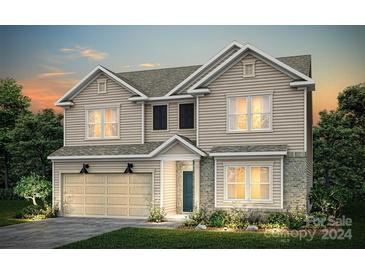 Two-story home with beige siding, two-car garage, and landscaping at 5207 Hatcher Creek Rd # 38, Charlotte, NC 28215