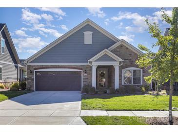 Ranch style home with stone and gray siding, two car garage, and landscaped lawn at 4014 Pleasant Run Dr, Matthews, NC 28104