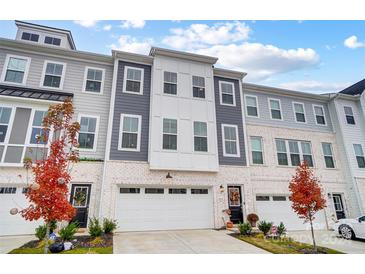 Three-story townhome with white and gray brick exterior, two-car garage, and landscaping at 4512 Forsyth Pl # 46, Fort Mill, SC 29707