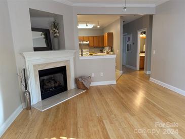 Living room with fireplace, hardwood floors, and kitchen peek at 19744 Feriba Pl, Cornelius, NC 28031