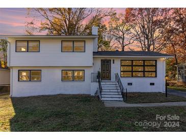 Stunning renovated home featuring a white brick exterior, updated landscaping, and a welcoming front porch at 6521 Heatherbrook Ave, Charlotte, NC 28213