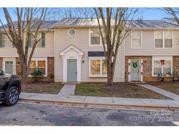 Two story townhome with light beige siding, green door and landscaping at 5212 Fair Wind Ln, Charlotte, NC 28212