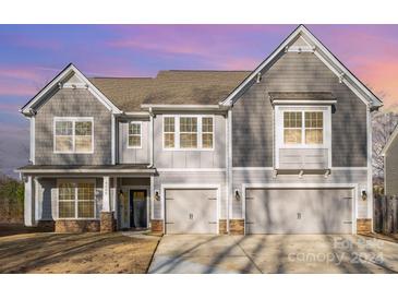 Two-story home with gray siding, three-car garage, and a landscaped yard at 9140 Cantrell Way, Huntersville, NC 28078