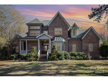 Brick two-story home at sunset with landscaping and covered porch at 2930 Phillips Fairway Dr, Charlotte, NC 28216