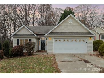 Beige house with white garage door and landscaping at 1824 Pipers Ridge Nw Cir, Conover, NC 28613