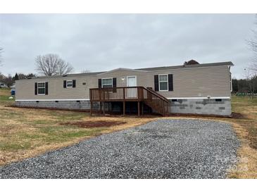 Tan mobile home with wood deck and gravel driveway at 3804 Crossing Creek Dr, Claremont, NC 28610