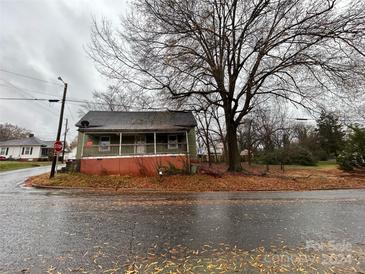 Green house with porch, situated on a corner lot with mature trees at 903 Efird St, Albemarle, NC 28001