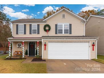 Two-story house with a beige exterior, a large garage, and a festive front porch at 3307 Tempo Ln, Indian Land, SC 29707