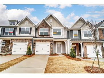 Three townhouses with gray siding, stone accents, and white garage doors at 4125 Black Ct # 169, Harrisburg, NC 28075