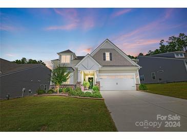 Charming two-story home with a welcoming front porch and landscaped yard at dusk at 1025 Dali Blvd, Mount Holly, NC 28120