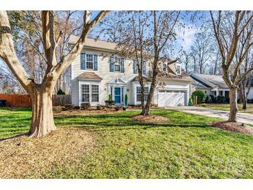 Two-story house with light beige siding, blue door, and landscaping at 13521 Toka Ct, Huntersville, NC 28078