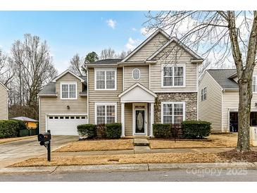 Two-story house with beige siding, stone accents, and a two-car garage at 14331 Lyon Hill Ln, Huntersville, NC 28078