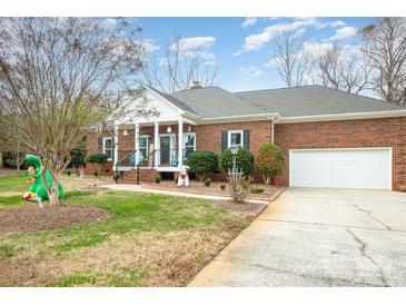 Brick ranch home with attached garage, covered porch, and holiday decorations at 8007 Stevens Mill Rd, Matthews, NC 28104