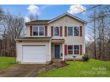 Two-story house with a beige exterior, red accents, and a two-car garage at 7 Riverside St, Lowell, NC 28098