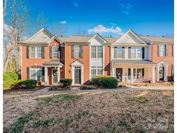 Three-unit townhome building, brick and white siding, landscaped lawn at 10859 Garden Oaks Ln, Charlotte, NC 28273