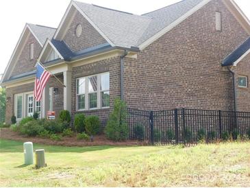 Brick home with American flag, landscaping, and black fence at 415 Newstyle Way # 6, Cramerton, NC 28056