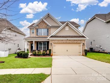 Two-story house with a large tan and brown brick facade, two-car garage, and well-manicured lawn at 7543 Hamilton Bridge Rd, Charlotte, NC 28278