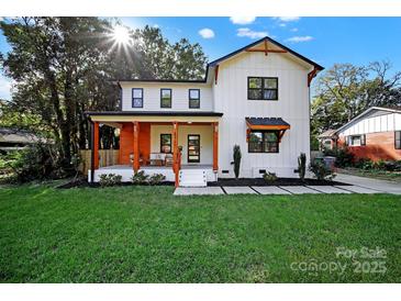 Two-story farmhouse style home with a front porch and landscaped lawn at 4122 Applegate Rd, Charlotte, NC 28209