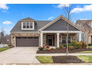 Gray-sided house with stone accents, brown garage doors, and manicured landscaping at 10118 Passau Path Dr, Huntersville, NC 28078