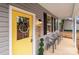 Porch with gray siding, yellow door, black shutters, and gray chairs at 310 New Bern Ave, Statesville, NC 28677
