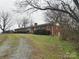 Brick ranch home on a spacious lot with a gravel driveway at 112 W Highway 218 Rd, Monroe, NC 28110
