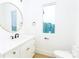 Clean and simple bathroom with white vanity, round mirror, and window view at 7362 Hemlock Ct, Denver, NC 28037