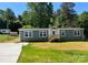 Gray mobile home with brick skirt, wooden steps, and a spacious yard at 111 Sweetwater Dr, Statesville, NC 28625