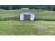 White storage shed with double doors in a grassy field at 24686 Barbees Grove Rd, Oakboro, NC 28129