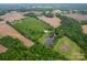 Aerial view showing expansive property with pond, outbuildings, and surrounding fields at 24686 Barbees Grove Rd, Oakboro, NC 28129