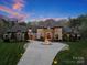 Elegant home with circular driveway and fountain at dusk at 9044 Island Point Rd, Charlotte, NC 28278