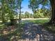 Gravel driveway leading to a wooded area with a small building at 10910 Archer Rd, Davidson, NC 28036