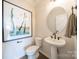 Stylish bathroom with pedestal sink, round mirror, and art at 5919 Wetlands Aly, Charlotte, NC 28215